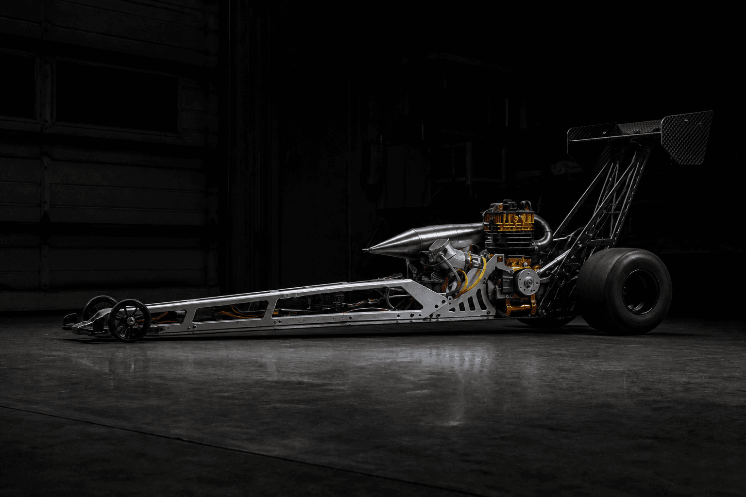 Large-scale gas RC dragster bare chassis with exposed frame rails and gold engine in a cinematic garage hero